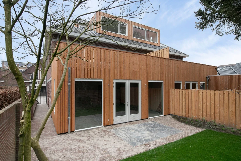 De uitbreiding met houten gevelbekleding aan de achterzijde van de pastorie.: Appartementen Best, beeld 2