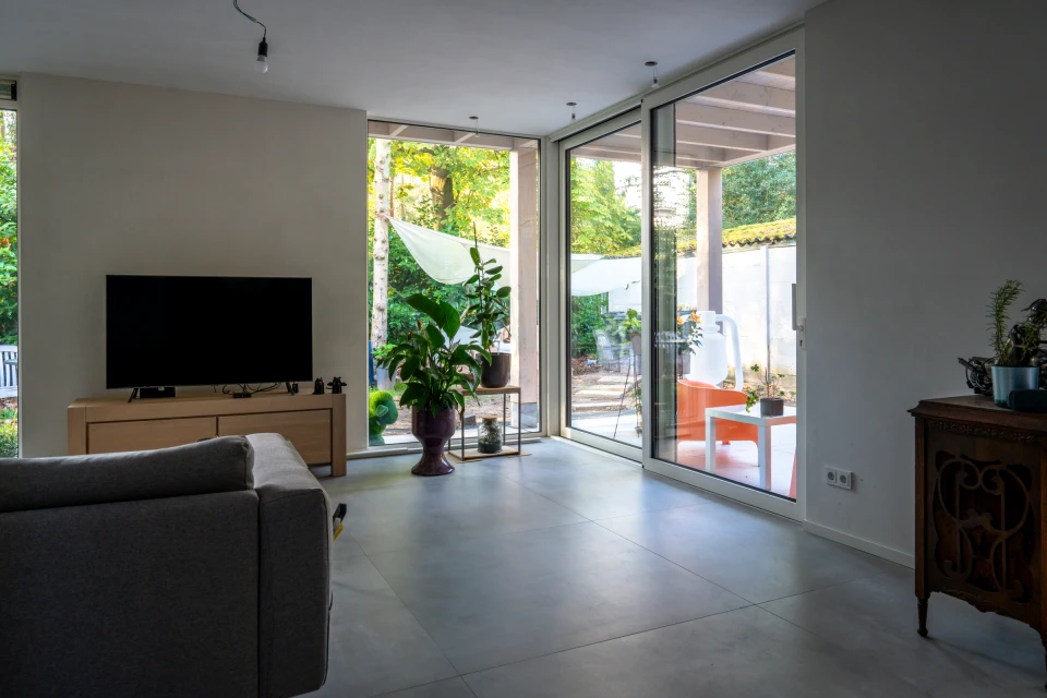 De woonkamer met zicht op de tuin en de overdekte buitenruimte in Best.: Woningverbouwing Best, beeld 3
