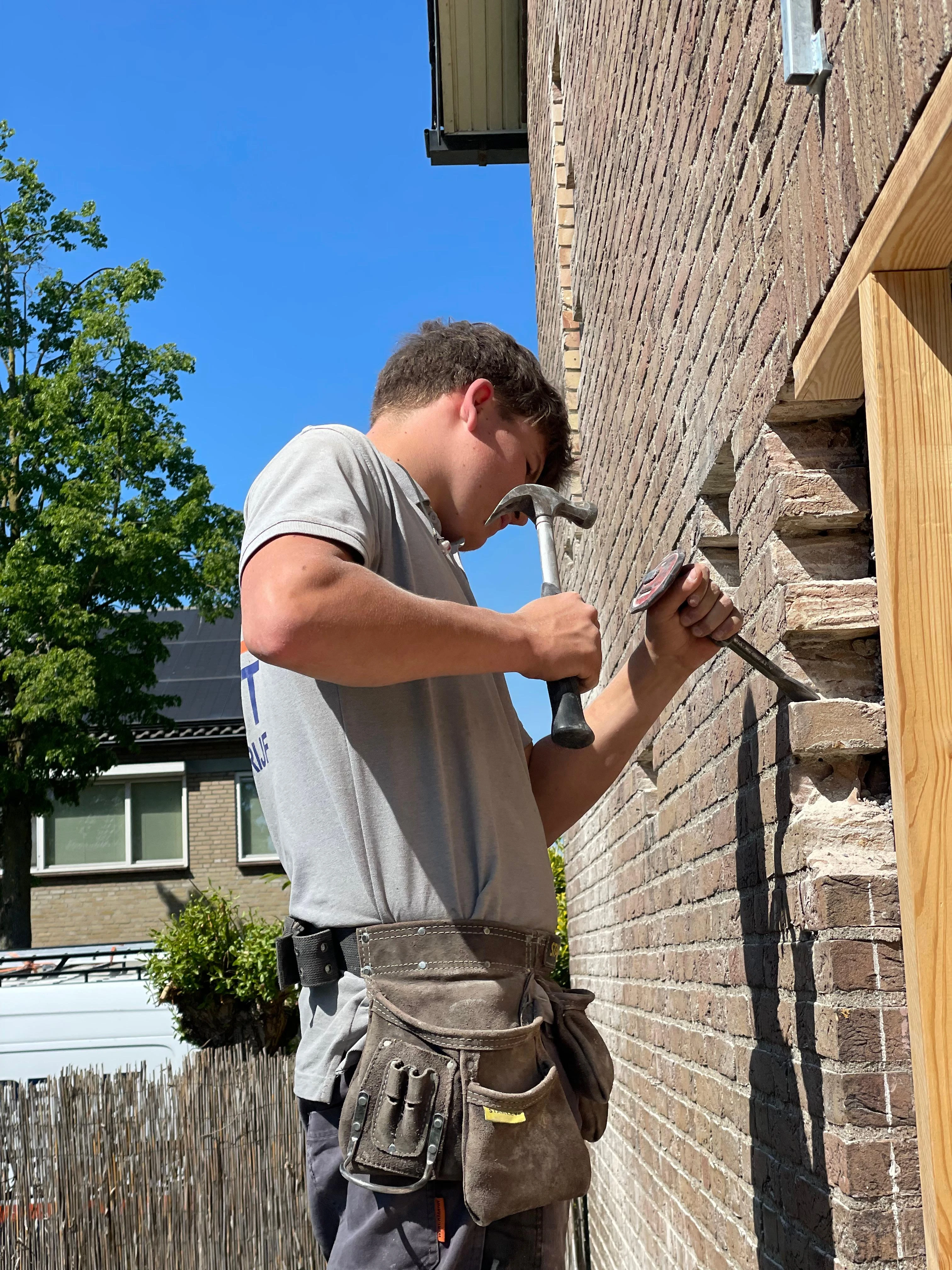 Een medewerker van De Wit Bouwbedrijf werkt aan een gemetselde gevel